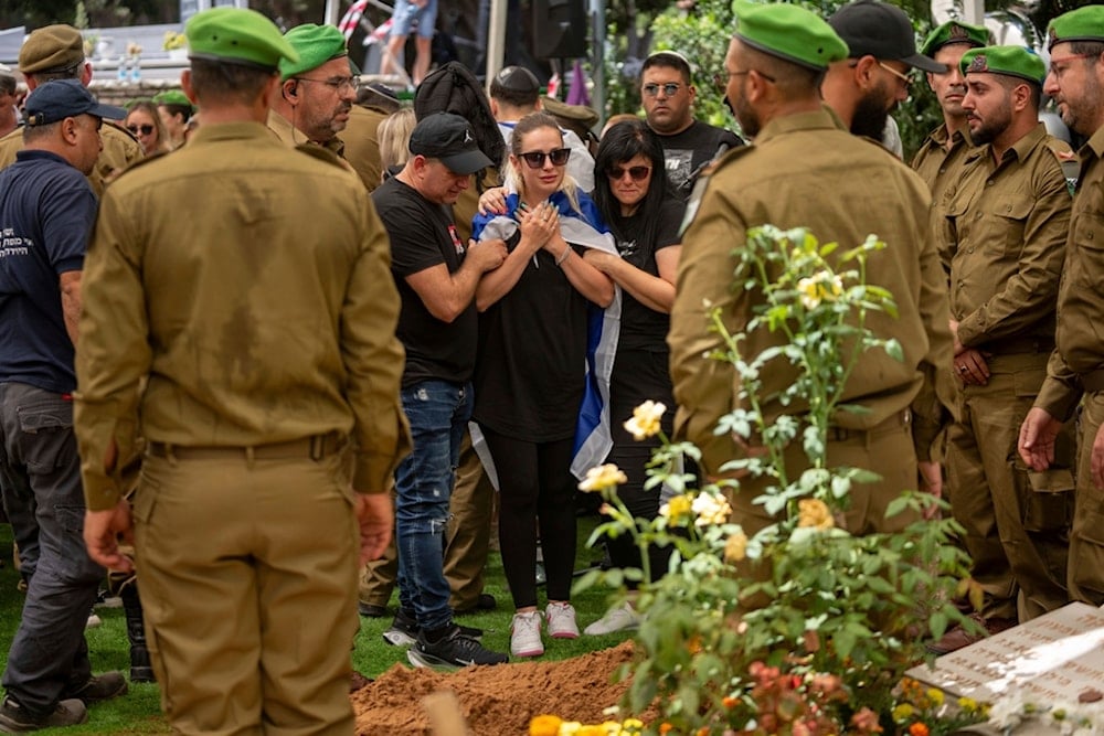 Family and the wife of an Israeli reservist gather around his grave during his funeral at the military cemetery in Netanya, occupied Palestine, on Friday, July 12, 2024 (AP)