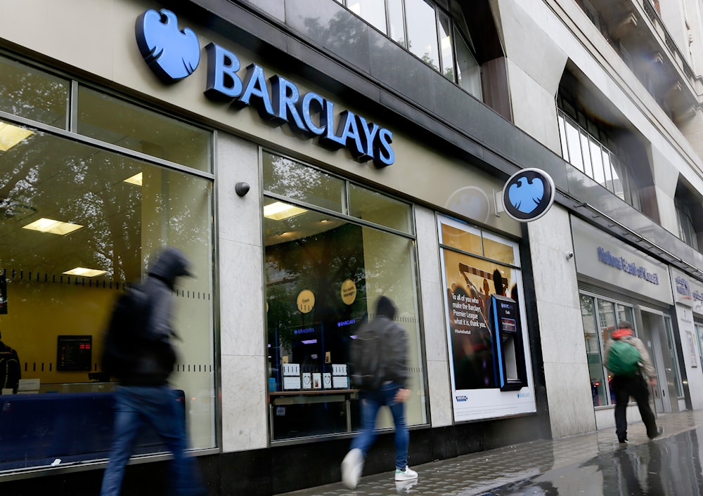 Pedestrians pass a branch of Barclays Bank in the rain in London, on May 8, 2014. (AP)