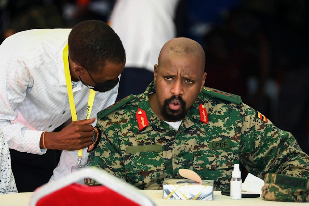 Lt. Gen. Muhoozi Kainerugaba, right, son of Uganda's President Yoweri Museveni, speaks to Attorney General Kiryowa Kiwanuka, left, at a 