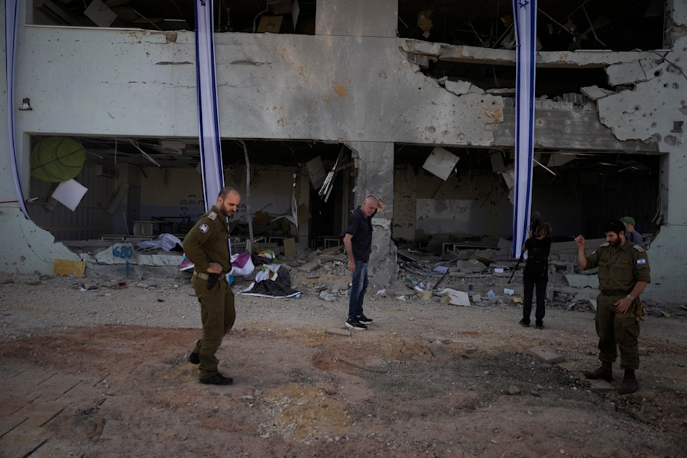 Israeli military and people look at a damaged building that was hit in Iran's missile attack in 