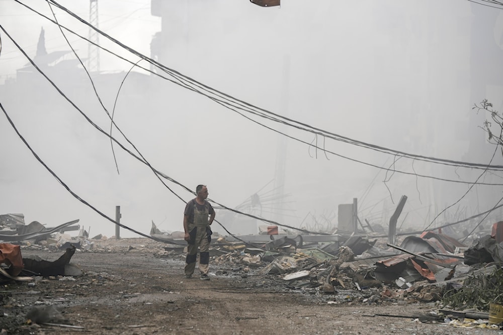 A man walks as smoke rises from destroyed buildings at the site of an Israeli airstrike in Choueifat, southeast of Beirut, Lebanon, Monday, October 7, 2024 (AP)