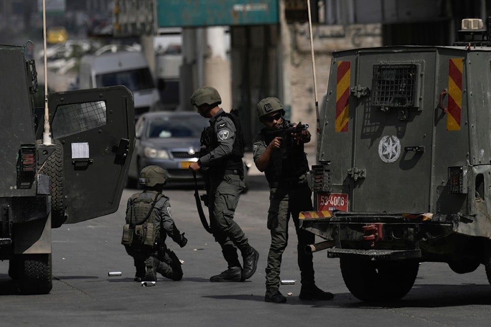 Israeli occupation forces stand near their vehicles during a military incursion into the West Bank refugee camp of Balata, occupied Palestine, Oct. 1, 2024. (AP)