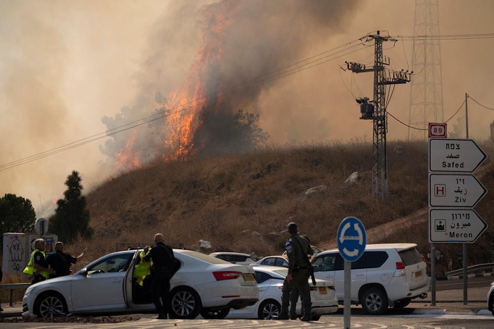 Members of the Israeli forces watch a fire after a rocket, fired from Lebanon, hit an area near the settlement of Rosh Pinna, northern occupied Palestine, Sunday, Oct. 20, 2024 (AP)