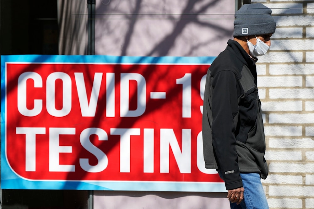 Covid test sign is displayed at a store as a pedestrian walks past in Chicago, Monday, March 11, 2024. (AP Photo/Nam Y. Huh)