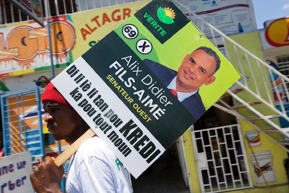 A supporter of the political party Platform Vérité carries a poster of parliamentary candidate Alix Didier Fils-Aime in Port-au-Prince, Haiti, Friday, Aug. 7, 2015. (AP)