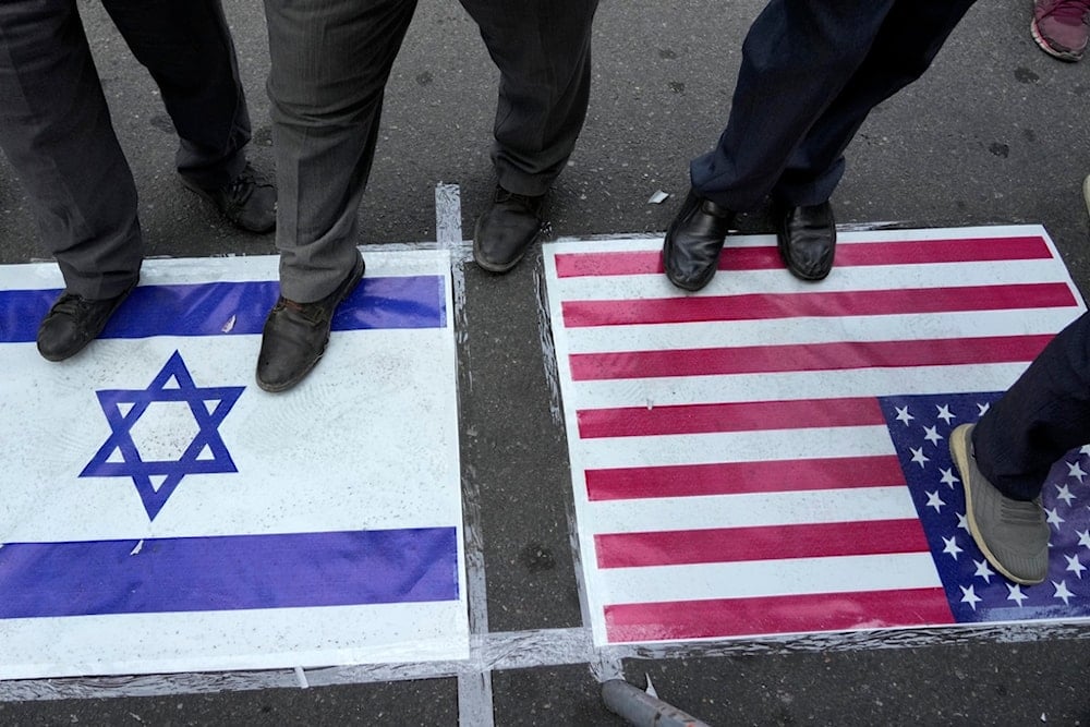 Iranian demonstrators stand on representations of the US and Israeli flags in an anti-Israeli gathering at Felestin (Palestine) Square in Tehran, Iran, Tuesday, October 8, 2024 (AP)