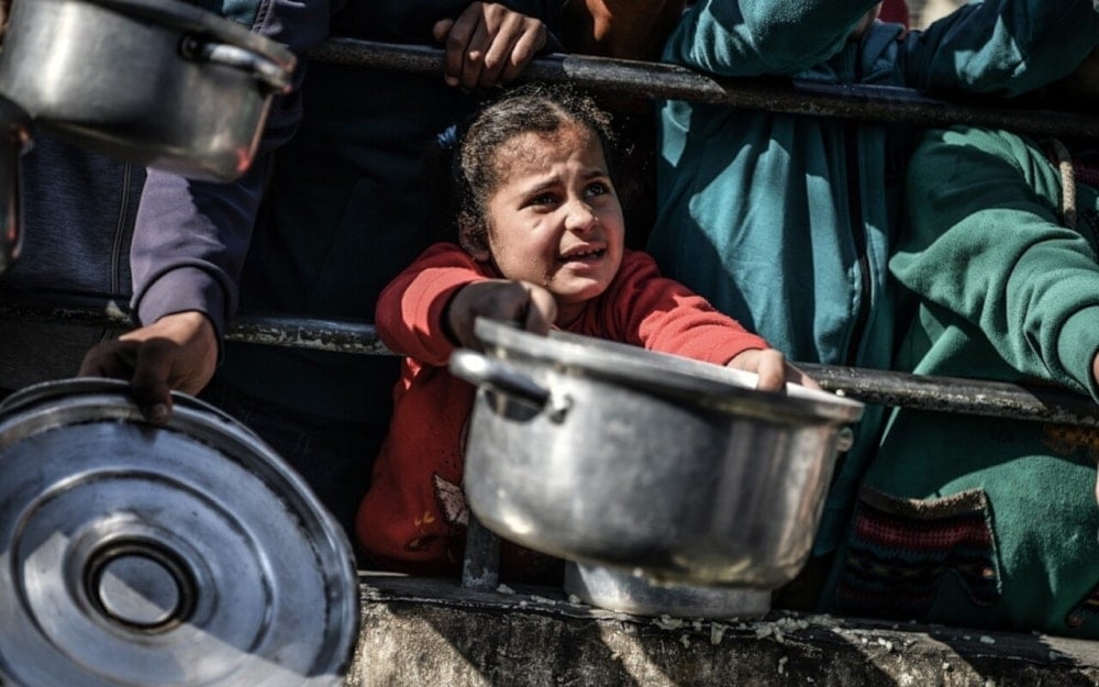 Shaima, 8-years-old, waits her turn in the crowd to get a meal from a charitable hospice that distributes free food in the city of Rafah, southern Gaza Strip (UNICEF)