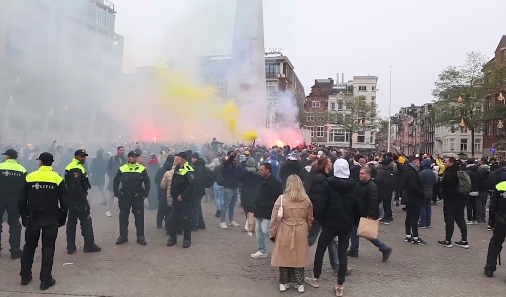 Police stand guard as Maccabi Tel Aviv supporters light flares at the Dam square, in Amsterdam, the Netherlands, on November 7, 2024. (AP)