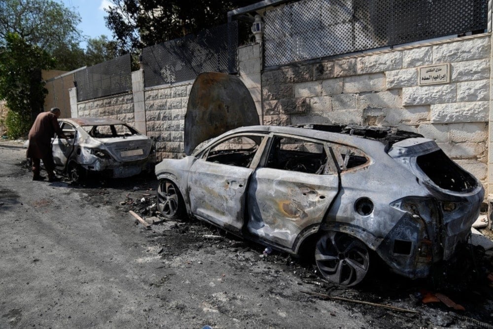 A Palestinian examines a torched vechile, seen the morning after a rampage by Israeli settlers in the West Bank village of Jit, on August 16,2024.(AP)