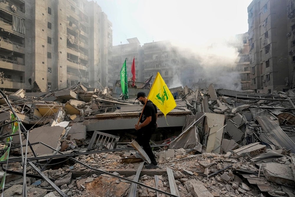 A man carries a Hezbollah flag as he walks on the rubble of his destroyed apartment following an Israeli airstrike in the Southern Subrub of Beirut, Lebanon, Friday, November 1, 2024 (AP)