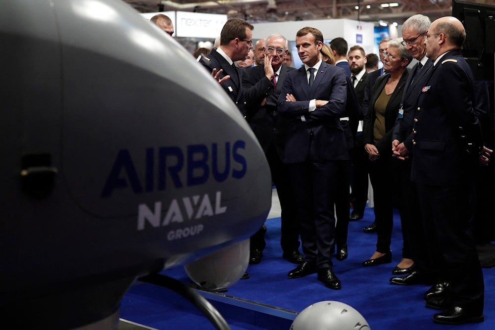 French President Emmanuel Macron (C) listens to explanations as he visits a stand at Euronaval, the world naval defense exhibition in Le Bourget near Paris, on October 23, 2018. (AFP)