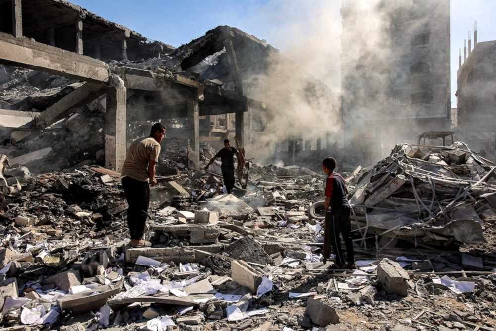 Palestinians walk through debris in a residential building bombed by 