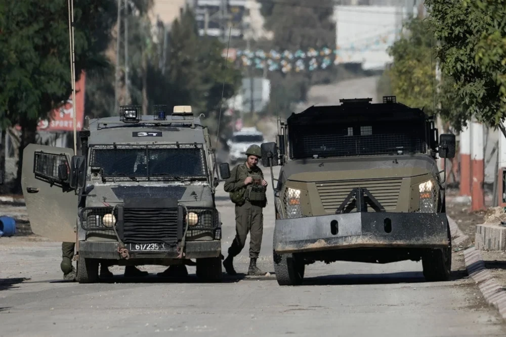 An Israeli occupation soldier stands by a vehicle during a raid in the West Bank of Jenin, on November 20, 2024. (AP)