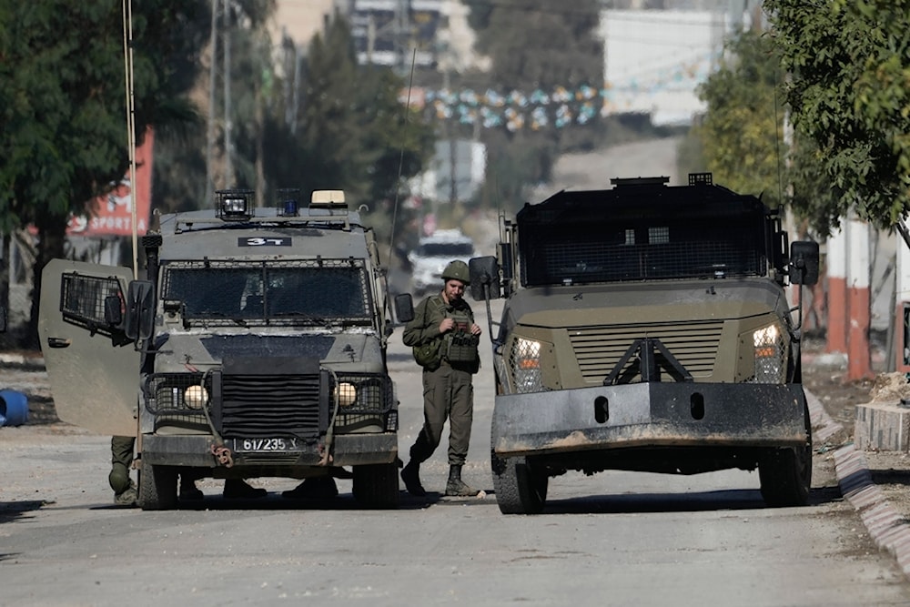 An Israeli soldier stands by vehicles during an incursion into the West Bank of Jenin, Wednesday, November 20, 2024 (AP)