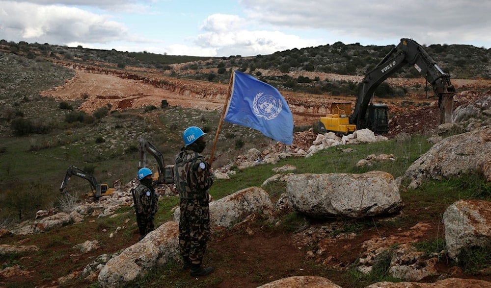 UN peacekeepers hold their flag, as they observe Israeli occupation forces conduct military operations, near the southern Lebanese border village of Mays al-Jabal, Lebanon, Dec. 13, 2019. (AP)