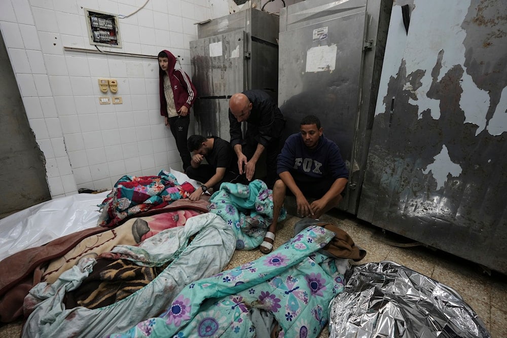 Palestinians mourn over relatives killed in an Israeli bombardment in Nuseirat, central Gaza, as they stand in a hospital morgue in Deir al-Balah, Gaza Strip, on November 20, 2024. (AP)