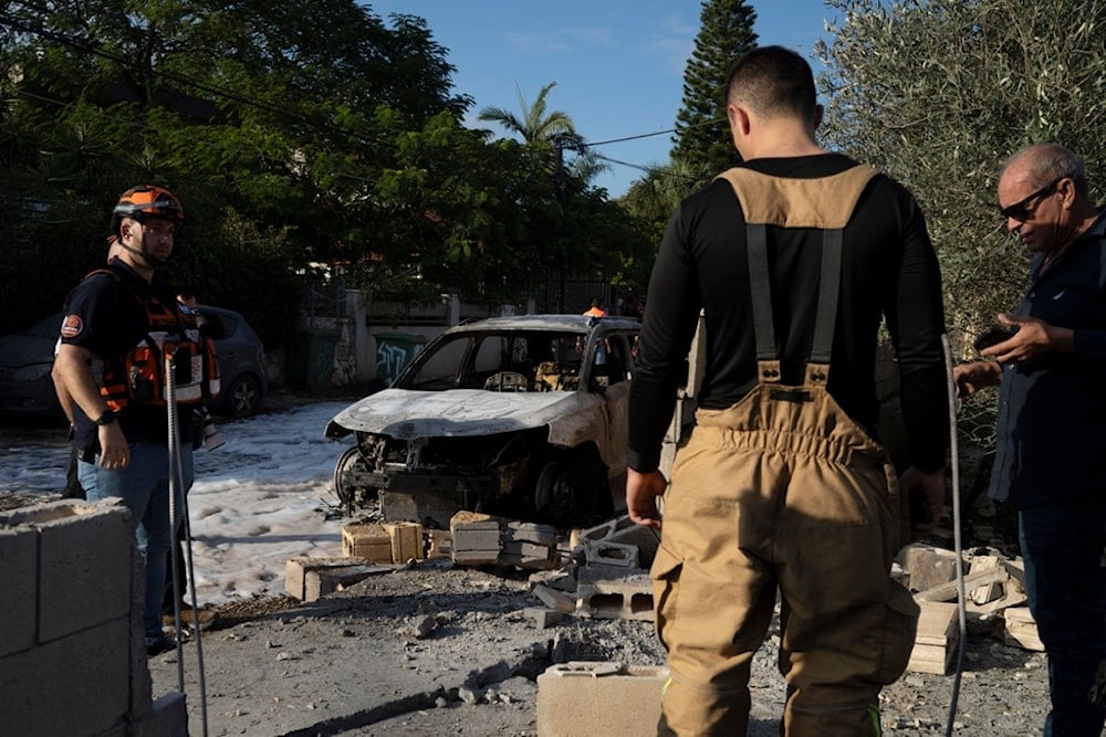 Rescue workers stand at the site where a rocket fired from Lebanon hit an area in Nahariya, northern occupied Palestine, Thursday, November 21, 2024 (AP)