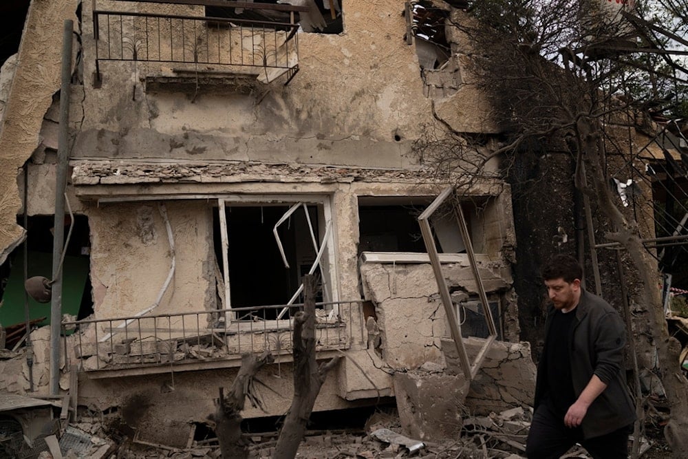 A settlers walks past a damaged building after a rocket fired from Lebanon hit an area in Rinatya, outskirts of Tel Aviv, occupied Palestine, Nov. 24, 2024. (AP)