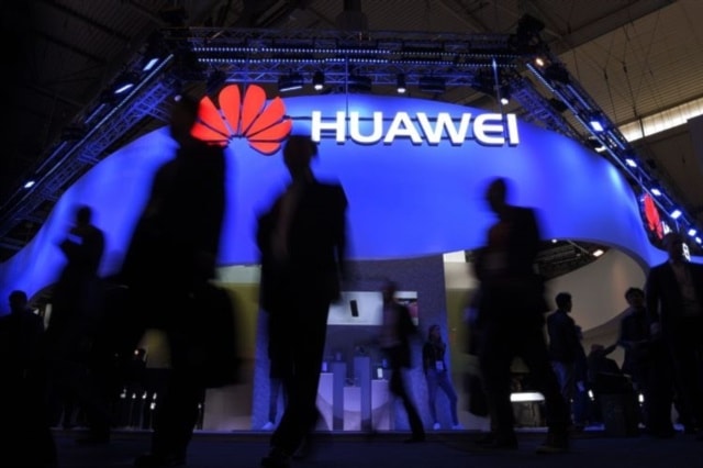 People walk next to a Huawei sign (AFP)