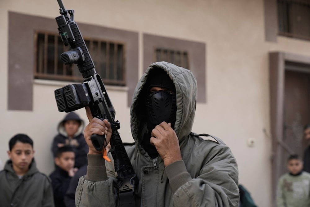 A Palestinian resistance fighter attends the funeral of Mohammad Hamarsheh, 13, and Ahmad Zaid, 20, killed during an Israeli military raid in the village of Yabad near the West Bank city of Jenin, Monday, November 25, 2024 (AP)