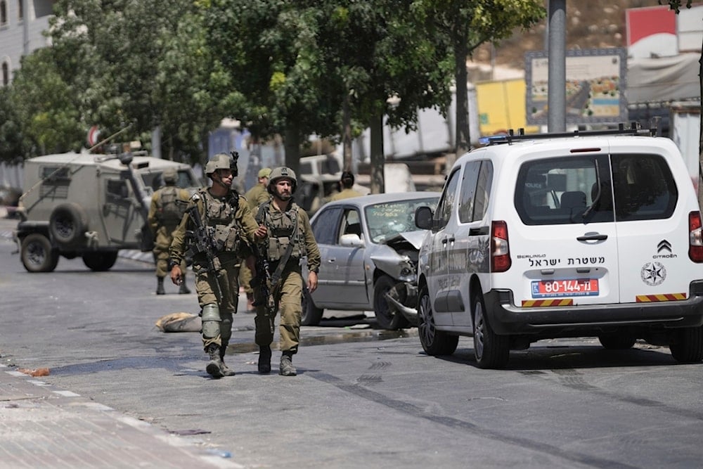 Israeli soldiers work at the site of an alleged car-ramming operation near Beit Hagai, a Jewish settlement in the hills south of al-Khalil, Aug. 30, 2023. )ِ؛(