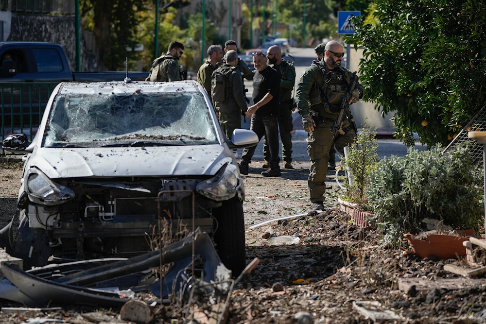 Israeli security officers and army soldiers inspect the site where a rocket fired from Lebanon landed in a backyard in Kiryat Shmona, northern 