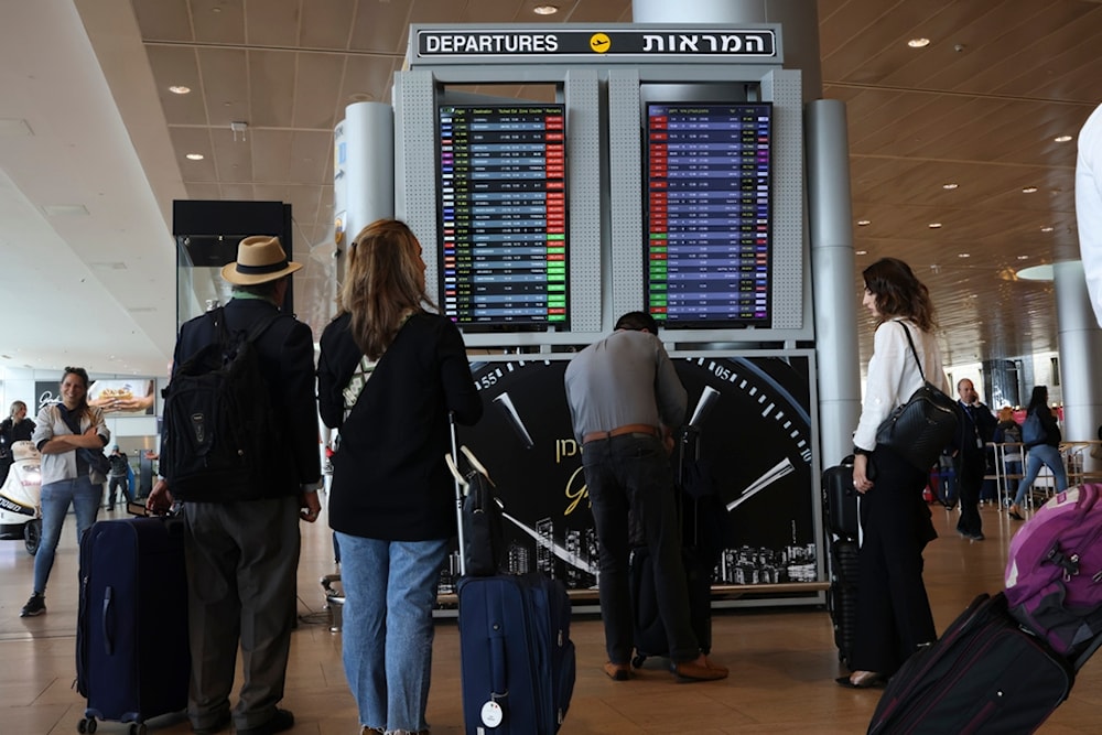 Israeli settlers and passangers look at the monitor displaying delayed flights at Ben Gurion airport, near Tel Aviv, 'Israel', Monday, March 27, 2023. (AP)