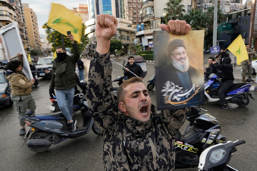 A man celebrates, carrying a picture of martyred Hezbollah leader Sayyed Hassan Nasrallah in the Southern Suburb of Beirut, Lebanon, following a ceasefire between the Israeli occupation and Hezbollah, Nov. 27, 2024 (AP)