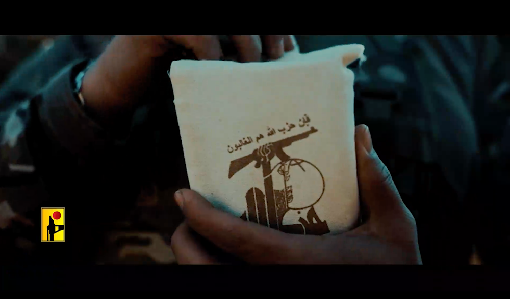 Screen grab from a Hezbollah propaganda video, showing a freedom fighter pulling out the Holy Quran from a pouch that reads the verse 