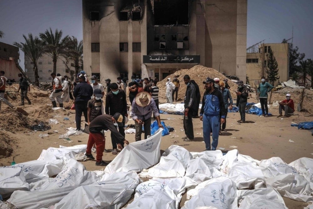 Palestinian health workers unearth a body buried by IOF in mass graves inside the Nasser hospital compound in Khan Younis in the southern Gaza Strip on April 21,2024. (AFP)