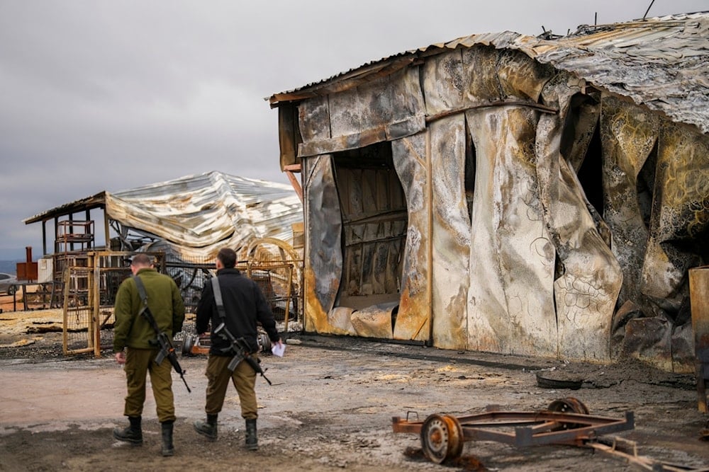 Israeli soldiers walk next to a damaged animal farm hit by a rocket fired from Lebanon in Avivim, northern occupied Palestine, near the border with Lebanon, Wednesday, Nov. 27, 2024. (AP)