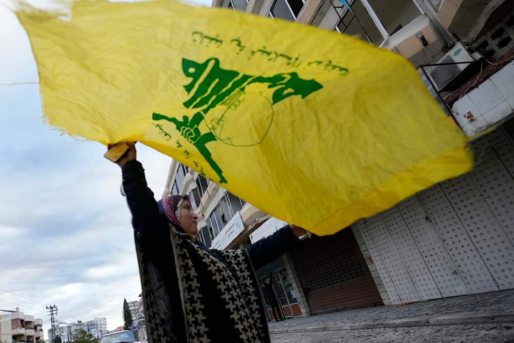 A woman waves a Hezbollah flag as she celebrates the ceasefire which began early morning, in Tyre, south Lebanon, Wednesday, Nov. 27, 2024. (AP)