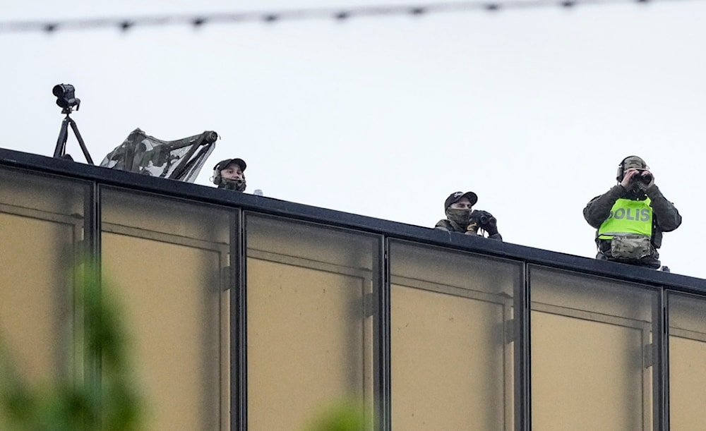 Police observe from a roof as people stand in line for the second dress rehearsal for the first semifinal at the Eurovision Song Contest in Malmo, Sweden, May 6, 2024. (AP)