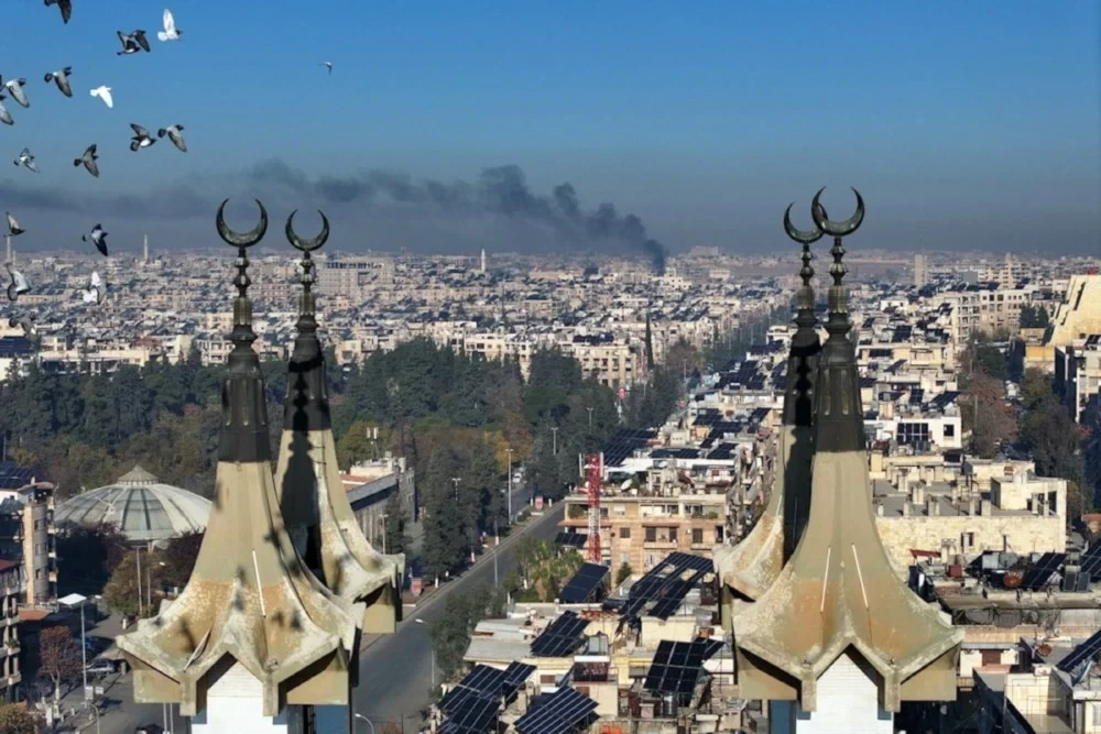 An aerial image of the city of Aleppo after militants entered, with smoke clouds visible in the background (AFP).