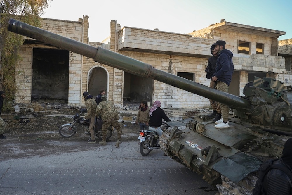 Syrian terrorists get on a motorcycle as opposition supporters stand on top of a captured army armored vehicle in the town of Maarat al-Numan, southwest of Aleppo, Syria, Saturday, November 30, 2024 (AP)