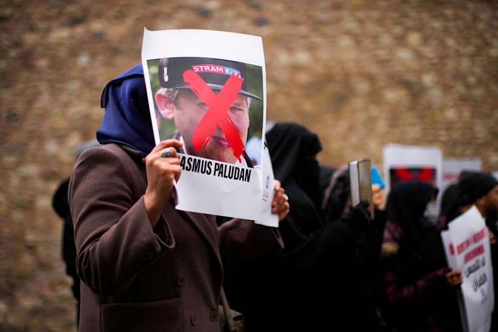 A woman holds a photograph of far-right activist Rasmus Paludan during a small protest outside the Swedish consulate in Istanbul, Turkey, Saturday, Jan. 28, 2023. (AP)