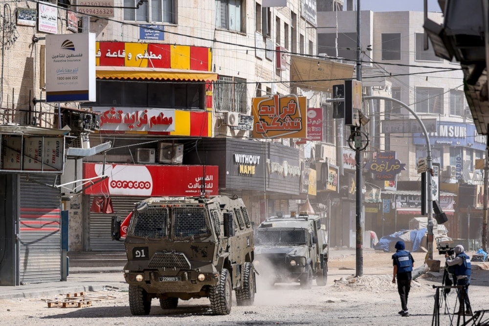 Journalists stand by to film as Israeli armored vehicles deploy during an IOF raid in the Jenin camp for Palestinian refugees in the north of the occupied West Bank, on October 14, 2024. (AFP)