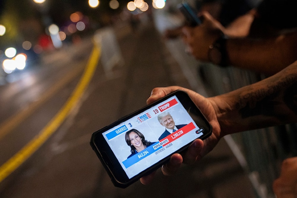 A member of the Metropolitan Police Department watches live election coverage outside of election night event for Democratic presidential nominee Vice President Kamala Harris at Howard University in Washington, Tuesday, November 5, 2023 (AP)