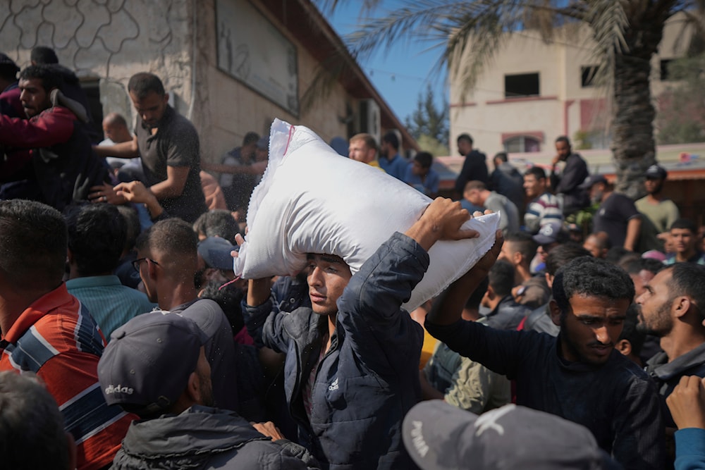 Palestinians gather to receive bags of flour distributed by UNRWA, the UN agency helping Palestinian refugees, in Deir al Balah, central Gaza Strip, on November 2, 2024. (AP)