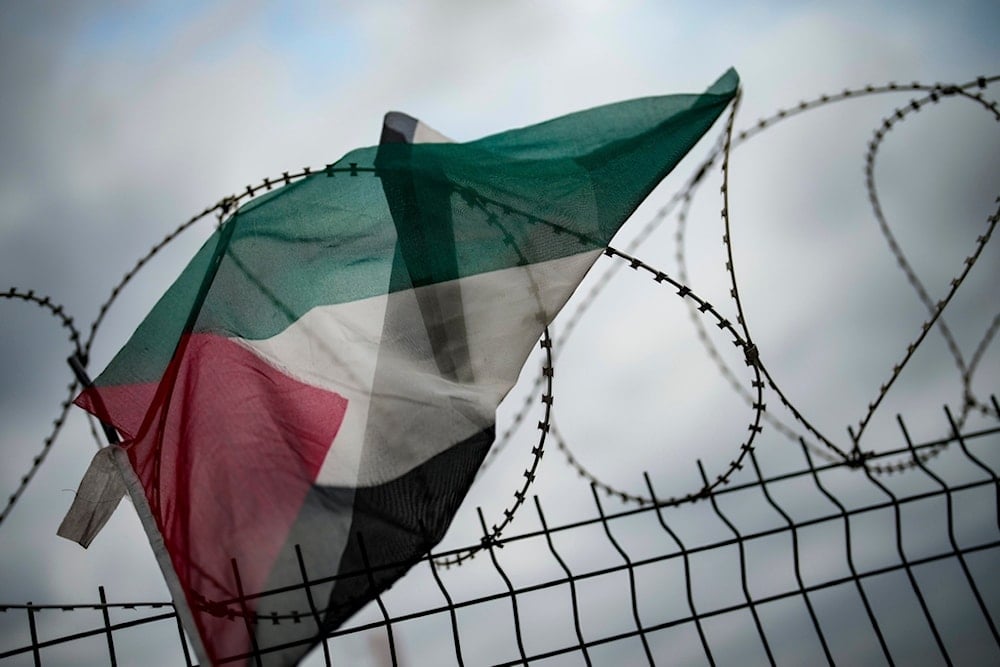 A Palestinian flag hangs in barbed wire as people march during a pro-Palestinian protest calling against the blockage by Turkish authorities of a ship loaded with aid to Gaza anchored at the Istanbul port, Sunday, December 1, 2024 (AP)