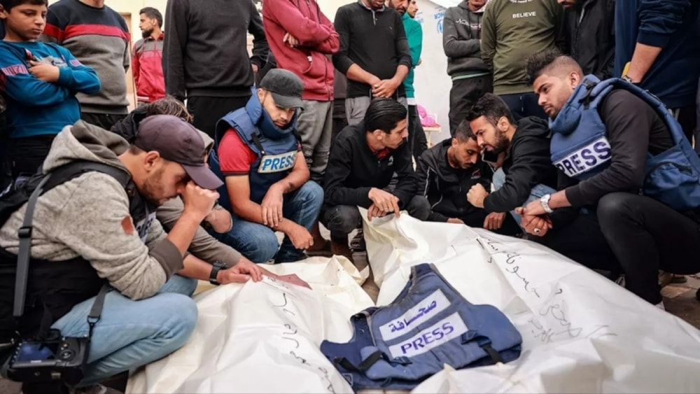 Friends and colleagues of two Palestinian journalists, Hasouna Slim and Sari Mansoor, killed in an Israeli strike, mourn over their bodies during their funeral in Deir al-Balah in southern Gaza, on November 19, 2023. (AFP)