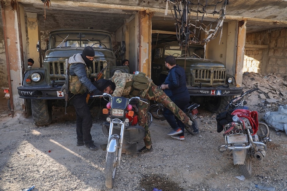 A terrorist checks a motorcycle next to abandoned army vehicles in the town of Maarat al-Numan, southwest of Aleppo, Syria, Saturday, November 30, 2024 (AP)