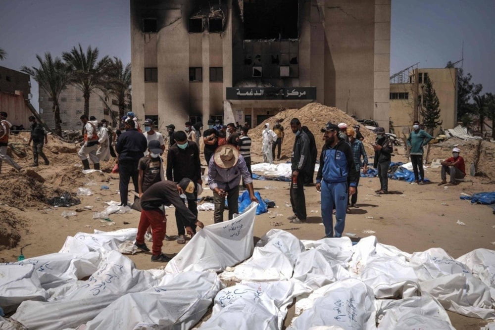 Palestinian health workers unearth a body buried by Israeli occupation forces in mass graves inside the Nasser hospital compound in Khan Younis in the southern Gaza Strip on April 21, 2024. (AFP)