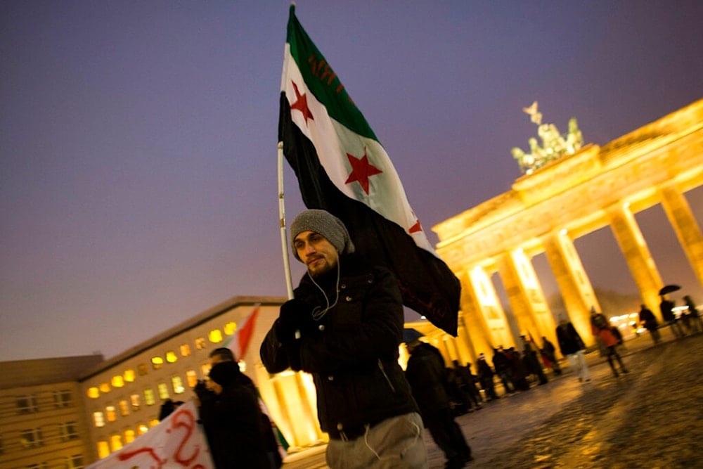 A man with a Syrian revolution flag attends a protest against the civil war in Syria and for a free Syria in front of the Brandenburg Gate in Berlin, Sunday, Dec. 23, 2012. (AP)