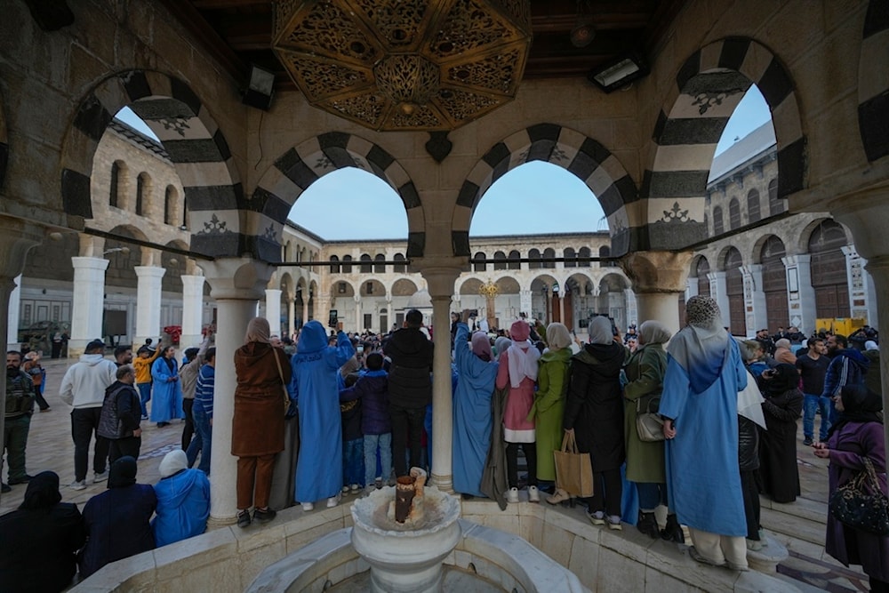 People watch and take photos with their cell phones as new regime supporters celebrate in the courtyard of the Umayyad Mosque in the old walled city of Damascus, Syria, on Tuesday, December 10, 2024 (AP)