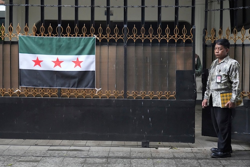 A security officer stands near a Syrian opposition flag on the gate of Syrian Embassy in Jakarta Tuesday, Dec. 10, 2024. (AP Photo/Achmad Ibrahim)