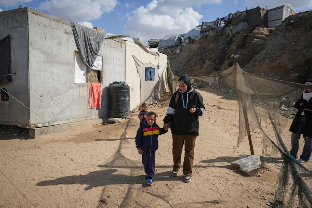 Reem Ajour walks with her son, Wael, at a camp outside Zuweida, Gaza Strip, November 20, 2024 (AP)