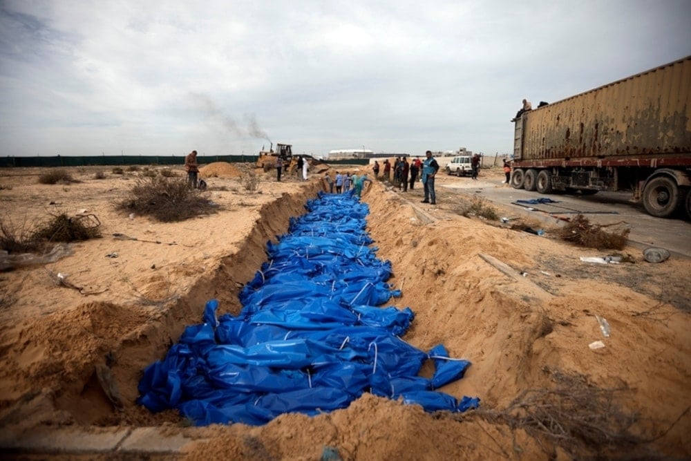 Palestinians bury people killed in the Israeli bombardment who were brought from the Shifa hospital, in a mass grave in the town of Khan Younis, southern Gaza Strip, Wednesday, Nov. 22, 2023 (AP)