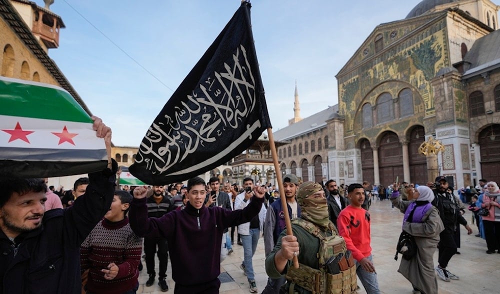 A masked opposition fighter carries a flag of Hayat Tahrir al-Sham (HTS) in the courtyard of the Umayyad Mosque in the old walled city of Damascus, Syria, on Tuesday, Dec. 10, 2024. (AP)