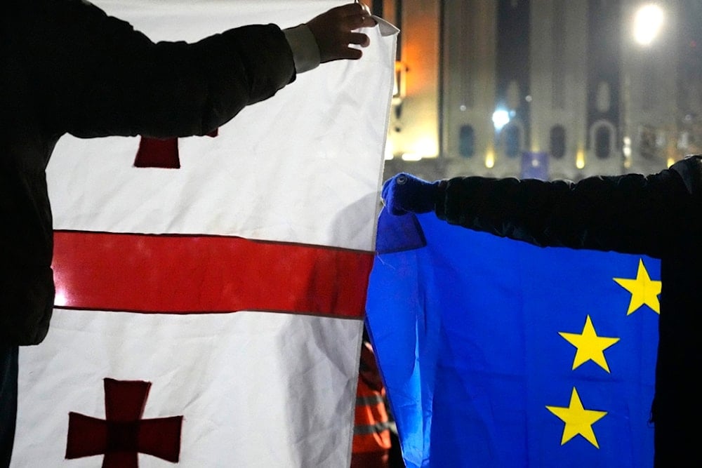 Demonstrators hold a EU, right, and Georgian flags during a protests against the government's decision to suspend negotiations on joining the European Union in Tbilisi, Georgia, Dec. 5, 2024. (AP)